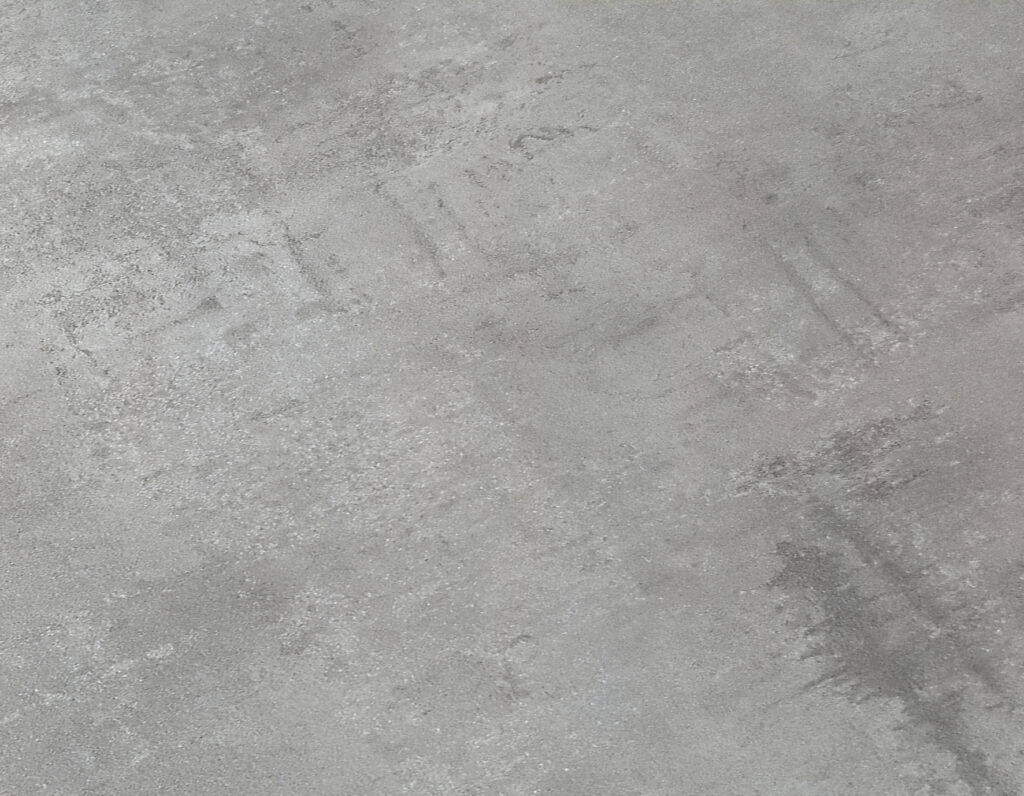 Dettaglio del piano in nobilitato effetto grigio cemento del tavolo allungabile
